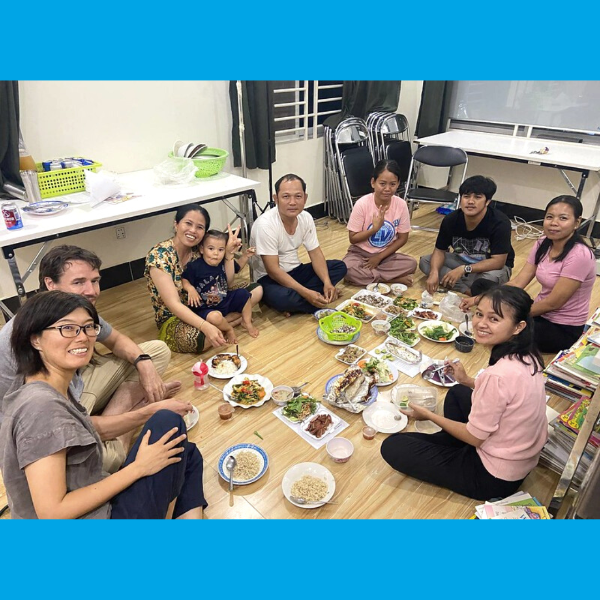 TukTuk staff, visitors and a toddler share a meal sitting on the office floor