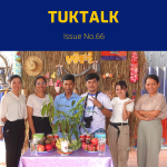 TukTalk 66 cover: TukTuk staff and visitors pose behind a table of fruit in front of a straw wall