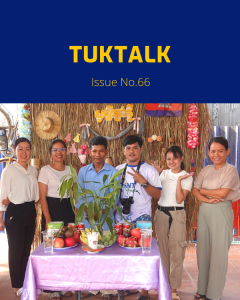 TukTalk 66 cover: TukTuk staff and visitors pose behind a table of fruit in front of a straw wall