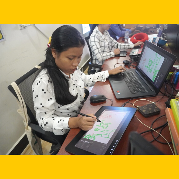 A young woman on the TukTuk team draws on a graphics tablet beside a laptop in the office