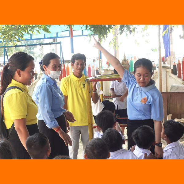 TukTuk staff and teachers stand with preschool children outdoors in a school playground