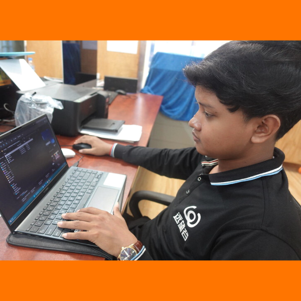 A young man on the TukTuk team works on a laptop at a desk in the office