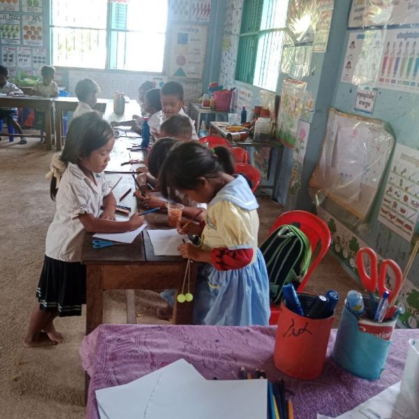 Preschool children stand at a table drawing and colouring in a classroom