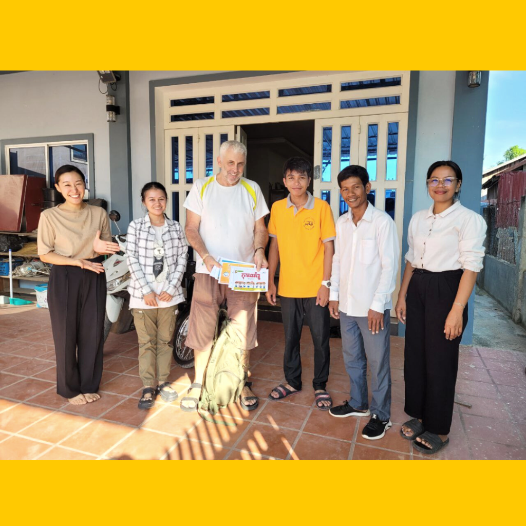 TukTuk staff and a visitor pose together on a house terrace, smiling and holding cards