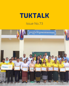 TukTalk 73 cover: teachers, officials and TukTuk staff hold framed certificates in front of a school building