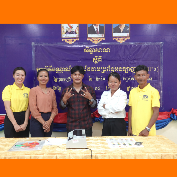 TukTuk staff and guests pose in front of the CLIP3 kick-off banner beside a laminator