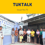 TukTalk 75 cover: TukTuk staff and visitors pose outside the office gate, one holding a small child