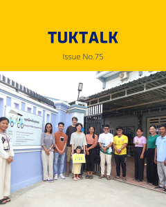 TukTalk 75 cover: TukTuk staff and visitors pose outside the office gate, one holding a small child