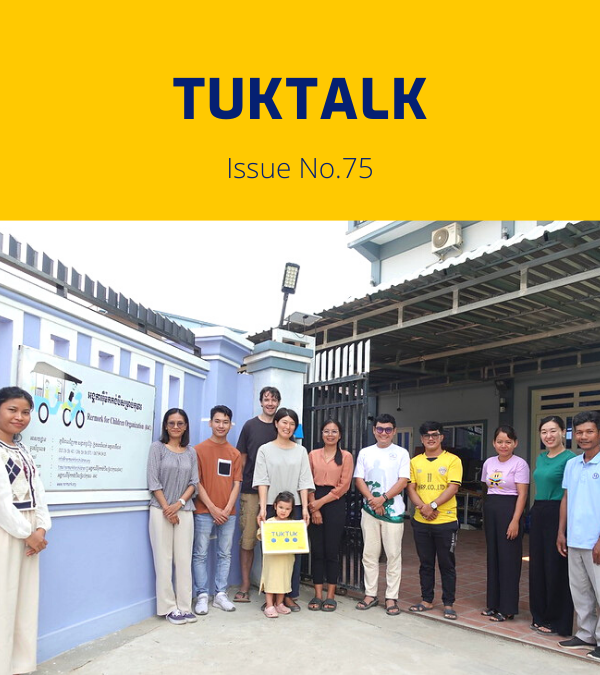 TukTalk 75 cover: TukTuk staff and visitors pose outside the office gate, one holding a small child
