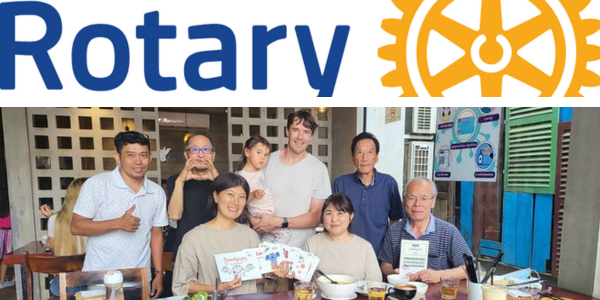 Rotary logo above a group photo of Omiya club visitors, TukTuk staff and a toddler at a table