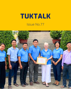 TukTalk 77 cover: TukTuk staff, a visiting Rotary volunteer and a local official hold a framed certificate on steps