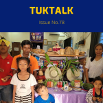 TukTalk 78 cover: adults and children pose beside a table of fruit, drinks and hats in the office