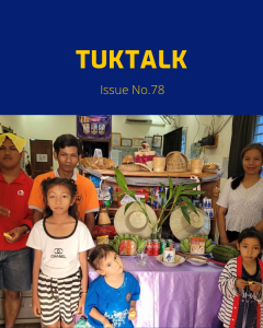TukTalk 78 cover: adults and children pose beside a table of fruit, drinks and hats in the office