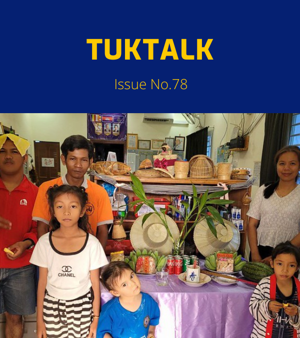 TukTalk 78 cover: adults and children pose beside a table of fruit, drinks and hats in the office