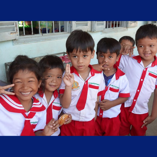 Smiling preschool children in school uniform pose and make peace signs for the camera