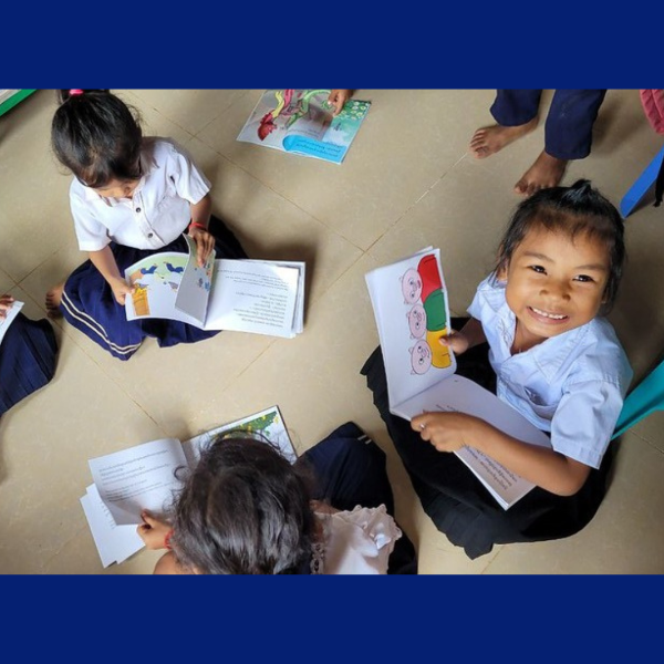 Children sit on the classroom floor reading and sharing TukTuk picture books
