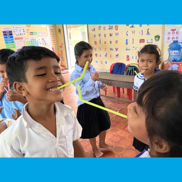 Children laugh while playing a game with bendy straws in a preschool classroom