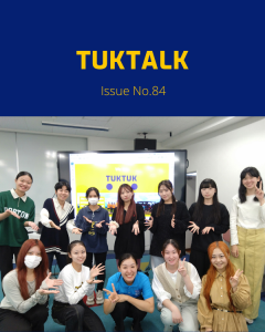 A TukTuk staff member poses with a group of students in front of a TukTuk presentation screen