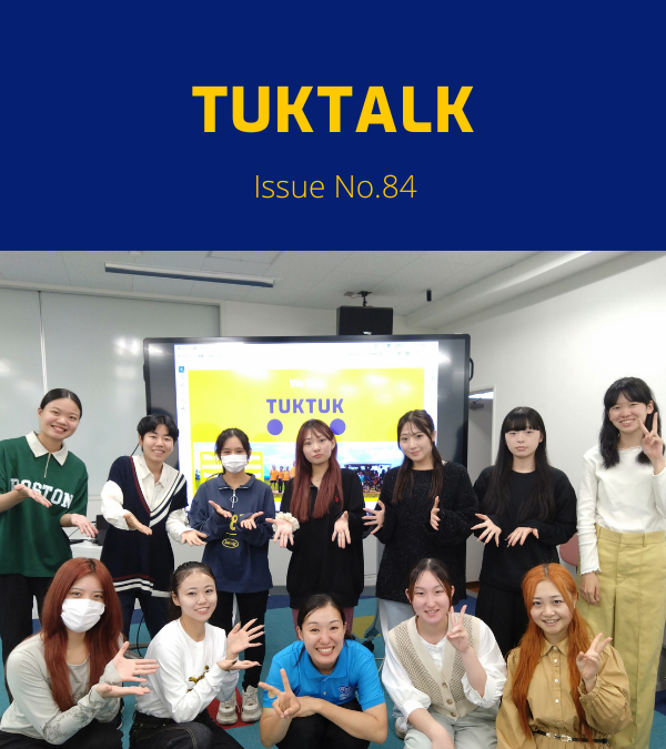 A TukTuk staff member poses with a group of students in front of a TukTuk presentation screen