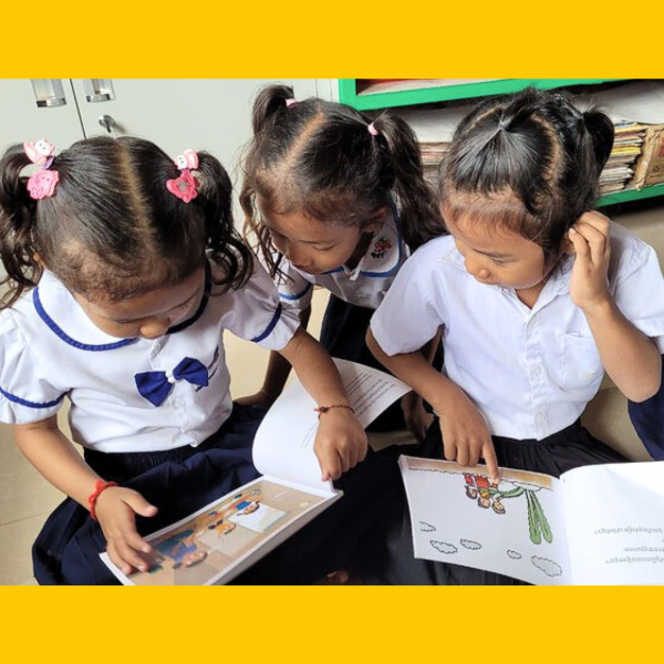 Three girls read TukTuk picture books together in their classroom