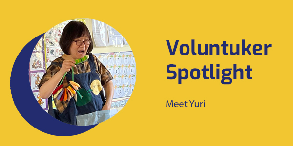 Portrait of Yuri, a storyteller and former preschool teacher, with an apron theatre puppet, titled Voluntuker Spotlight