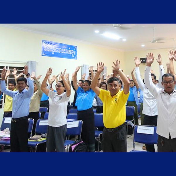 Teachers and officials raise their arms together during an energiser at the CLIP3 annual meeting