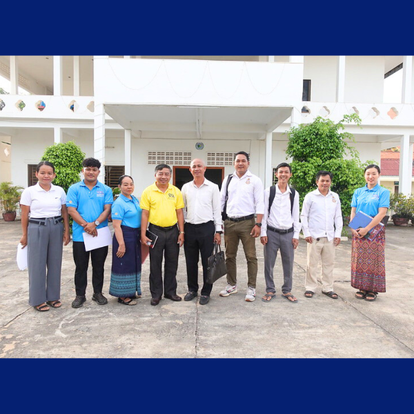 TukTuk staff, teachers and education officials stand together in front of a school building