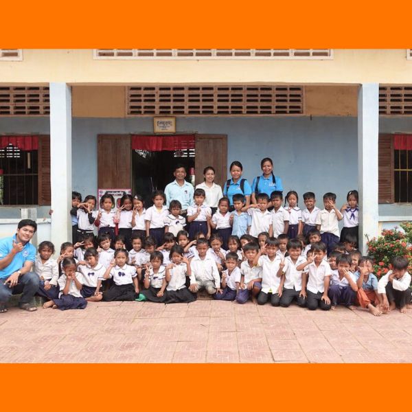 TukTuk staff and teachers pose with a large group of preschool children outside their school