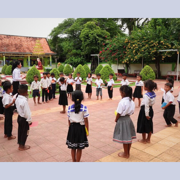 Children stand in a circle for an outdoor game in a school courtyard