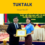 TukTalk issue 87 cover: a TukTuk staff member holds a certificate beside an official on stage at the provincial conference