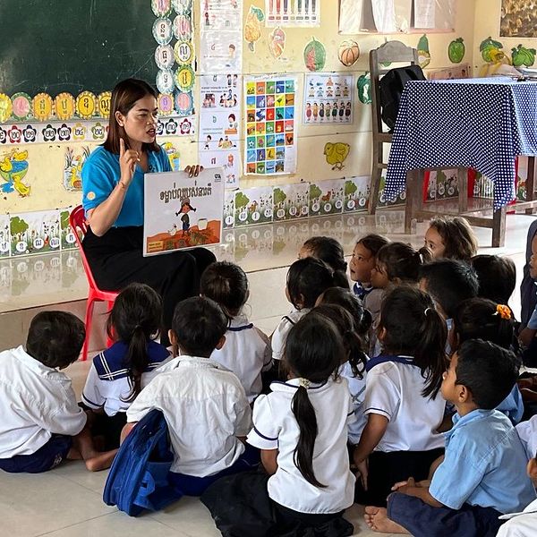 A teacher reads a picture book to preschool children seated on the classroom floor