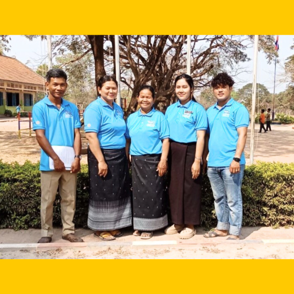 TukTuk staff and teachers pose together in front of a school