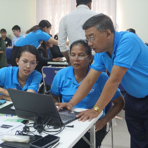 TukTuk staff and teachers work together on a laptop at a workshop