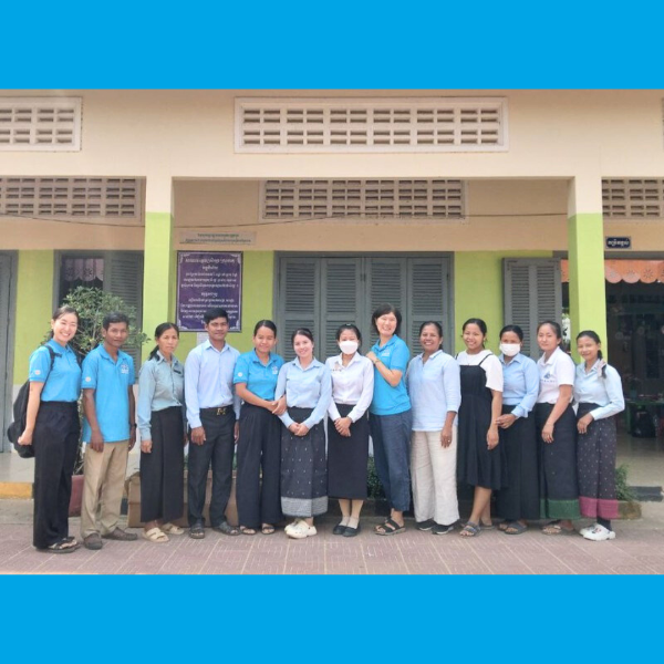 TukTuk staff and teachers pose in a row in front of a school building