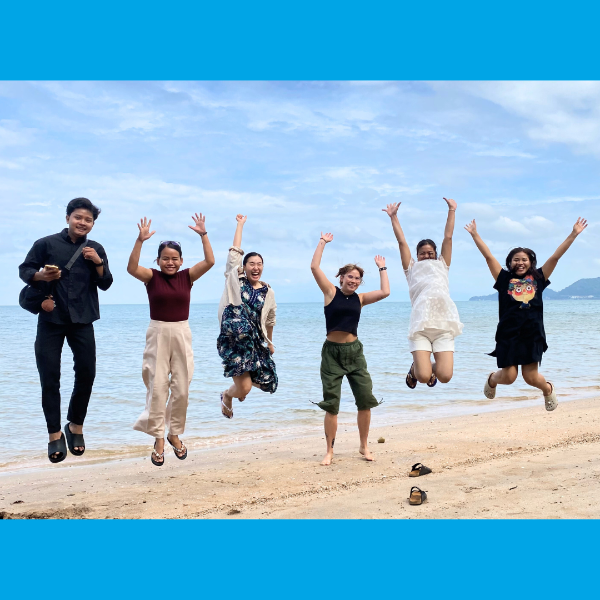 TukTuk staff jump in the air together on a beach during the staff trip