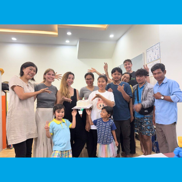 TukTuk staff, volunteers and children gather around a birthday cake in the office