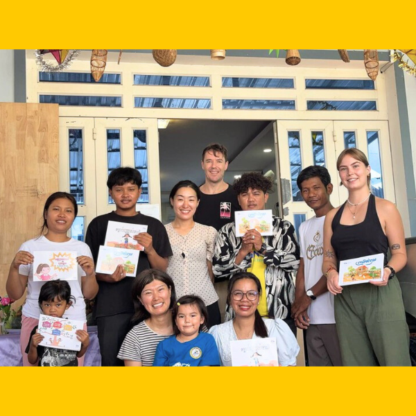 Volunteers and TukTuk staff hold up picture-book pages outside the new studio