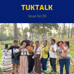 TukTuk staff and family members pose together among pine trees on the staff trip