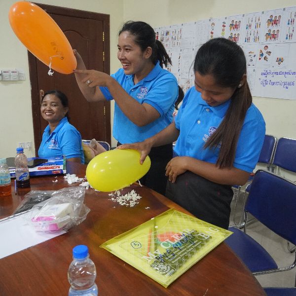 Teachers play with balloons and craft materials at a workshop table