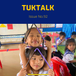 Two preschool girls smile and hold triangle shapes made from coloured sticks in a classroom