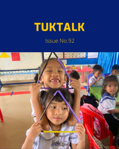 Two preschool girls smile and hold triangle shapes made from coloured sticks in a classroom