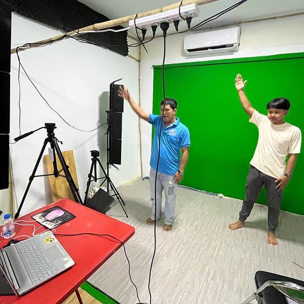 TukTuk staff try out the new green-screen studio, raising their arms in front of the backdrop
