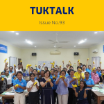 Teachers at the final workshop cheer and hold up yellow paper crafts in a classroom