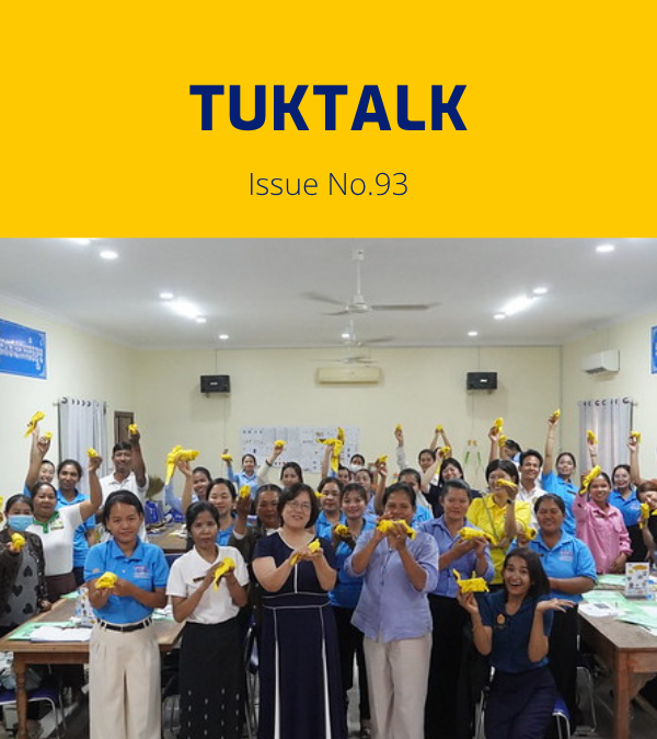 Teachers at the final workshop cheer and hold up yellow paper crafts in a classroom