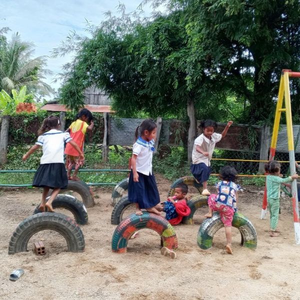 Children climb and play on painted tyres in a school playground