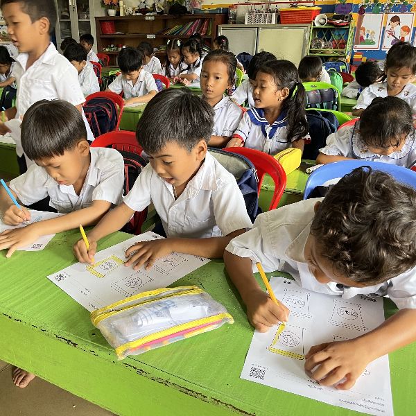 Children colour and trace worksheets at a green classroom table