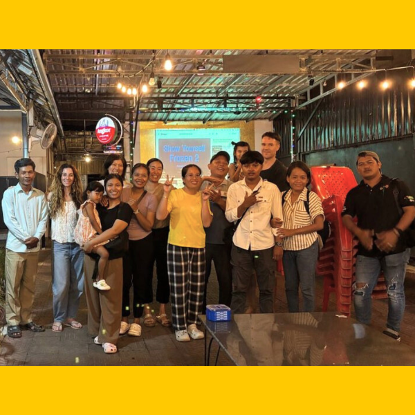 TukTuk staff and volunteers pose together at an evening gathering in a café