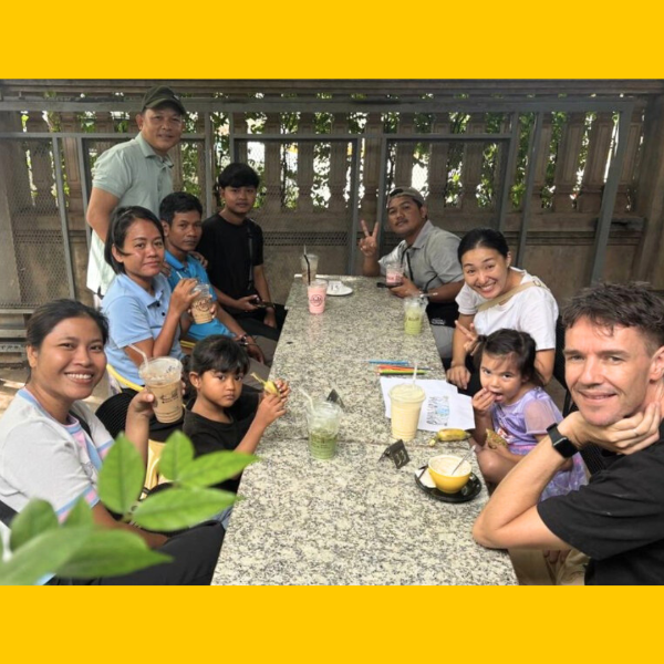TukTuk staff, volunteers and children share drinks around a table at a café