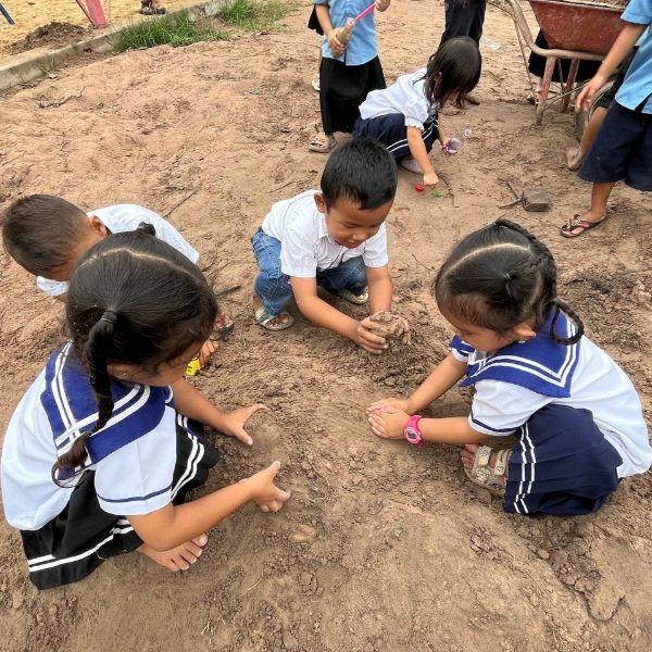 Preschool children dig and play in the sand and mud in the school yard