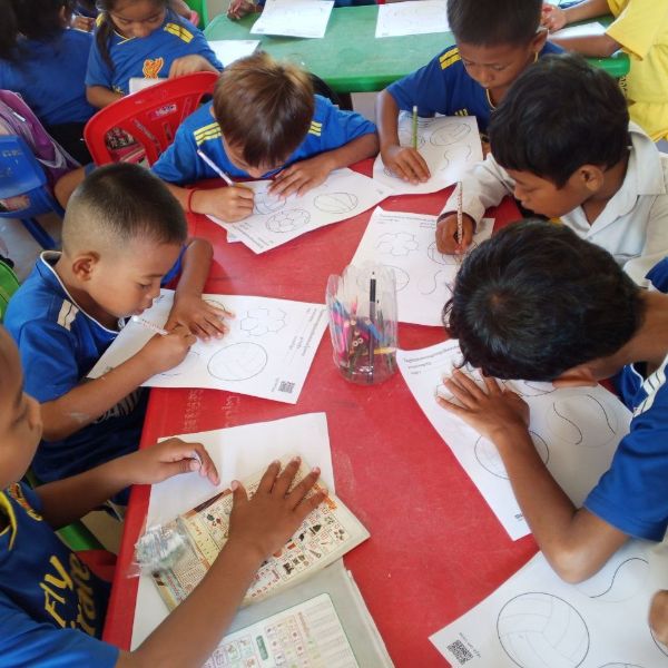 Children colour worksheets together at a red classroom table